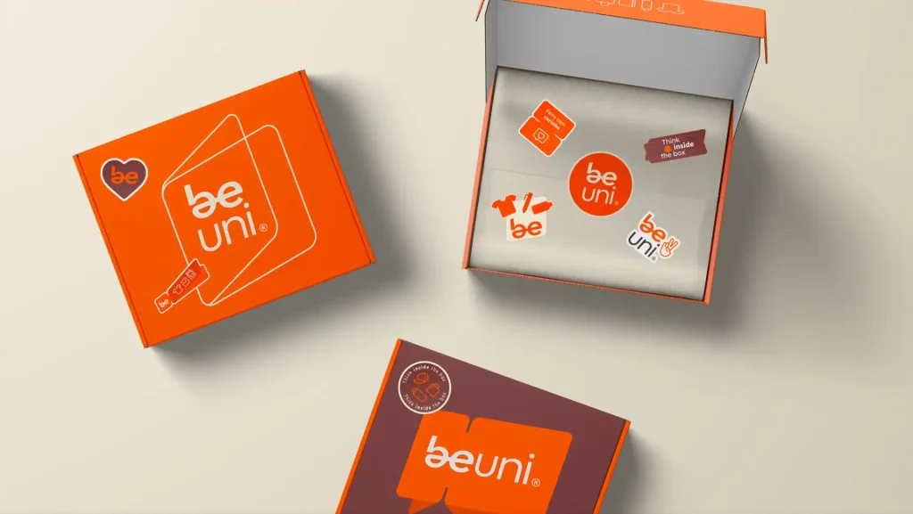 Caixas da beuni apresentando um design vibrante em laranja, com adesivos e elementos de marca evidentes, ideal para promoção e identidade visual.